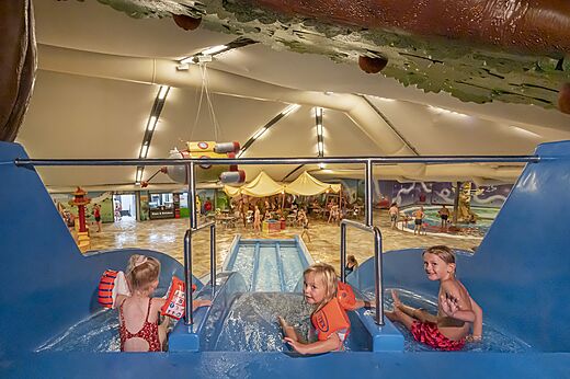 Kinder auf Indoor-Wasserrutsche und Schwimmbad auf Campingplatz CAPFUN De Bongerd Tuitjenhorn.