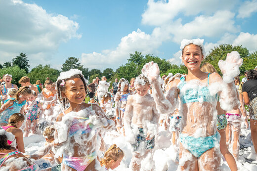 Lachende kinderen genieten van een bruisend schuimfeest op camping CAPFUN De Bongerd in Tuitjenhorn.
