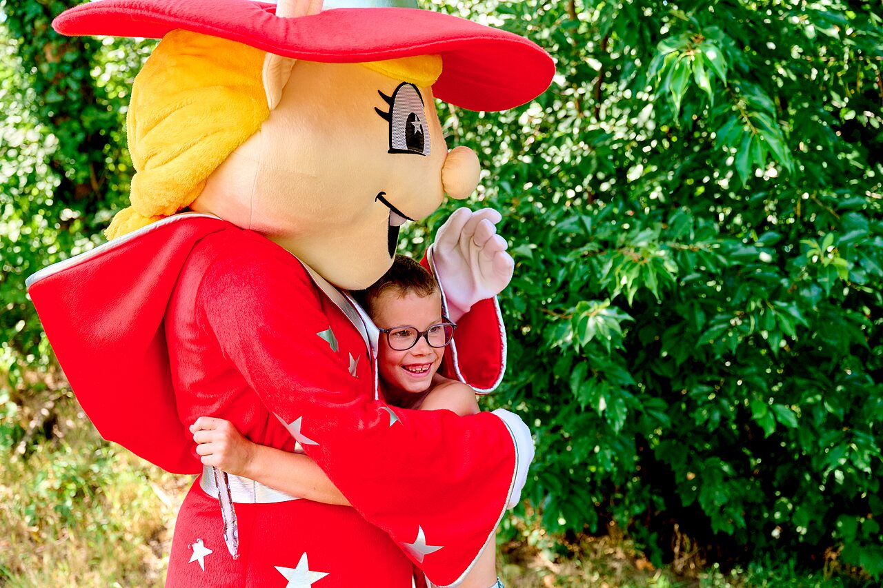 L�chelndes Kind umarmt Maskottchen auf dem Campingplatz CAPFUN De Eikenhof in Paasloo/Oldemarkt.