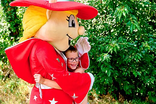 Maskottchen umarmt l�chelndes Kind auf dem Campingplatz CAPFUN De Eikenhof in Paasloo/Oldemarkt.