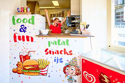 L�chelnde junge Frau hinter der Theke der Snackbar "Food & Fun" auf dem Campingplatz CAPFUN De Eikenhof in Paasloo/Oldemarkt.