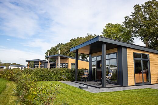 Mobil-homes modernes avec terrasses et chaises au camping CAPFUN De Eikenhof à Paasloo/Oldemarkt.