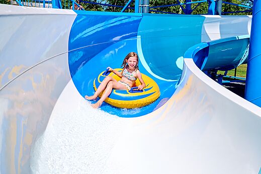 L�chelndes M�dchen rutscht Wasserrutsche mit Reifen auf Campingplatz CAPFUN De Eikenhof in Paasloo/Oldemarkt.