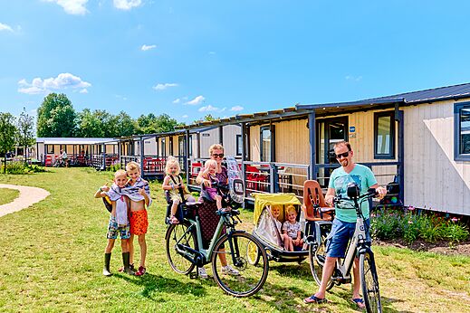 Familie mit Fahrr�dern vor Mobilheimen auf dem Campingplatz CAPFUN De Eikenhof in Paasloo/Oldemarkt.