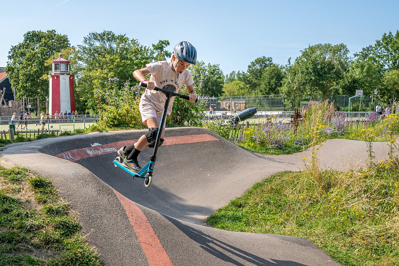 Kind auf Roller auf Pumptrack auf Campingplatz CAPFUN De Pekelinge in Oostkapelle.