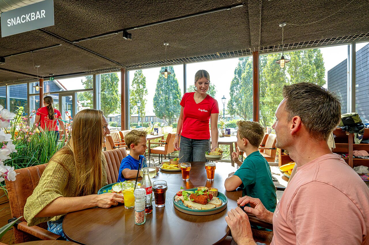Familie isst im Imbiss des Campingplatzes CAPFUN De Pekelinge in Oostkapelle.