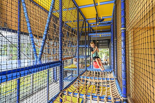 Lachend kind speelt in overdekte speelstructuur op camping CAPFUN De Pekelinge in Oostkapelle.