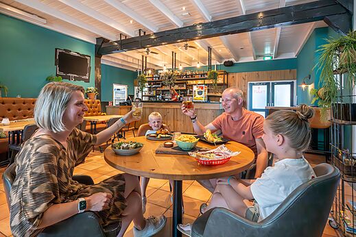 Famille souriante dînant au restaurant du camping CAPFUN De Pekelinge à Oostkapelle.