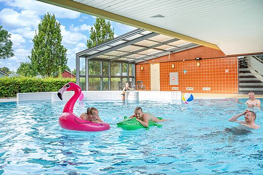 Überdachtes und Freibad mit Familie und aufblasbaren Spielzeugen auf dem Campingplatz CAPFUN De Pekelinge in Oostkapelle.