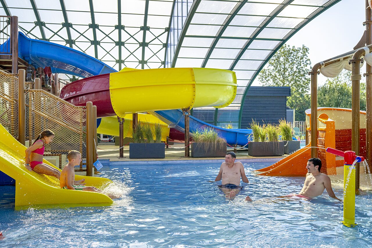 Toboggans aquatiques color�s et piscine couverte avec enfants et adultes au camping CAPFUN De Rotonde � Enspijk.