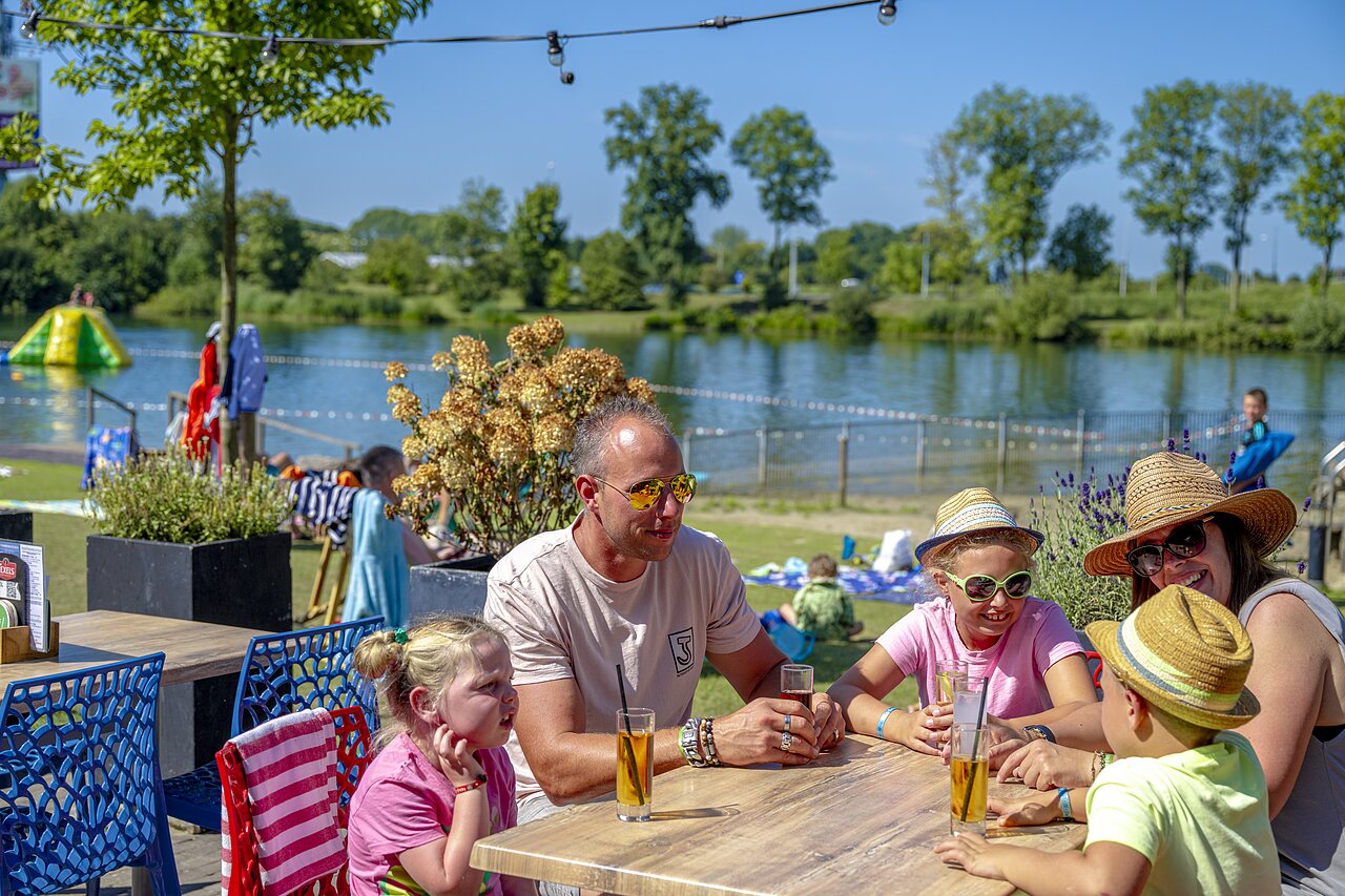 Famille en terrasse, lac, aquapark au camping CAPFUN De Rotonde � Enspijk.