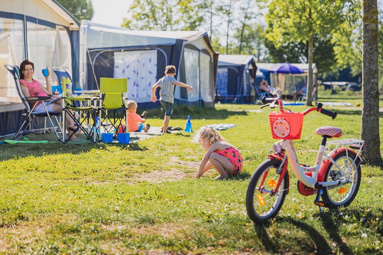 Emplacement de camping familial avec enfants jouant et v�lo au camping CAPFUN De Rotonde � Enspijk.