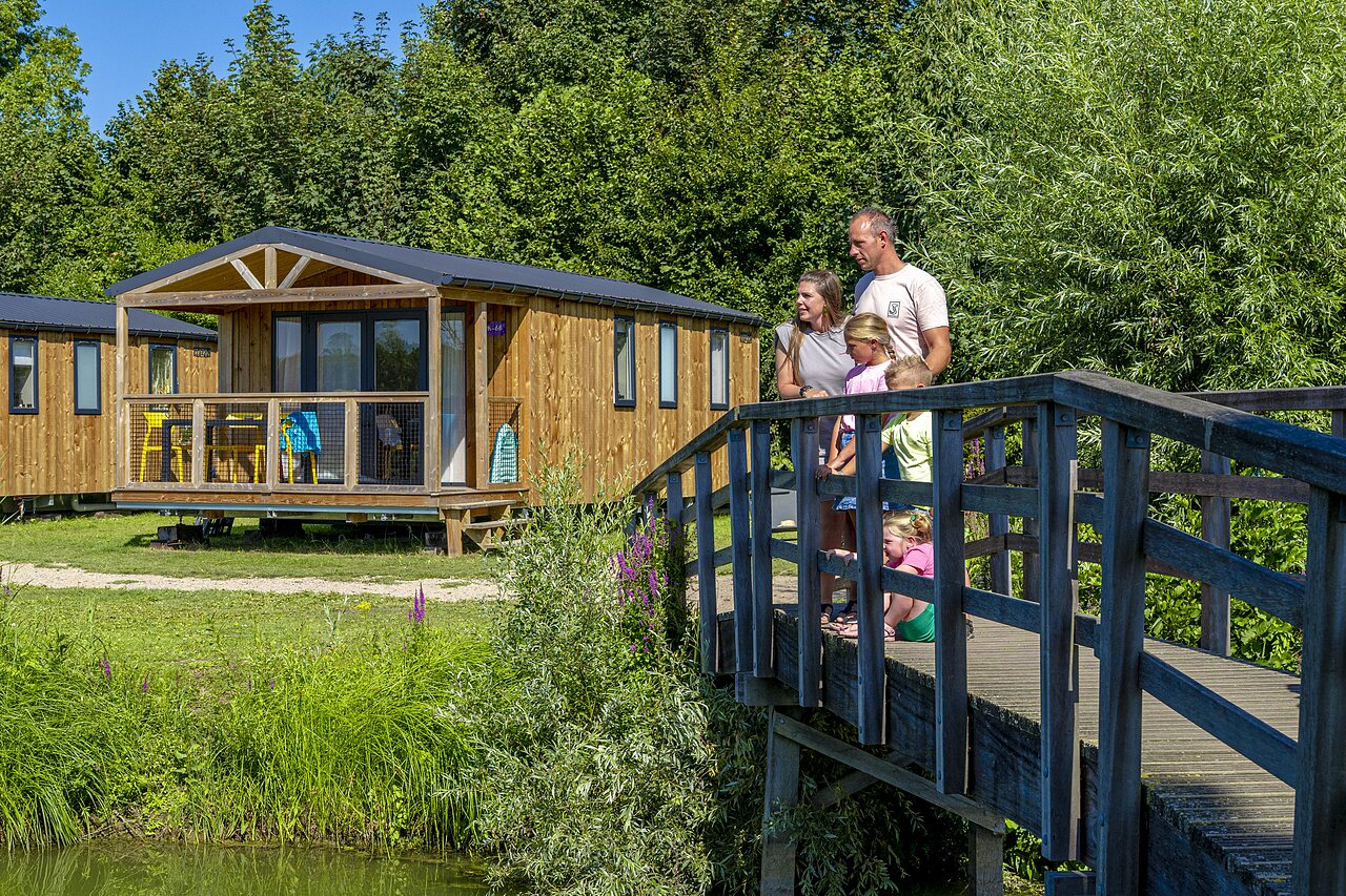 Famille sur pont en bois, mobile-homes, verdure au camping CAPFUN De Rotonde � Enspijk.