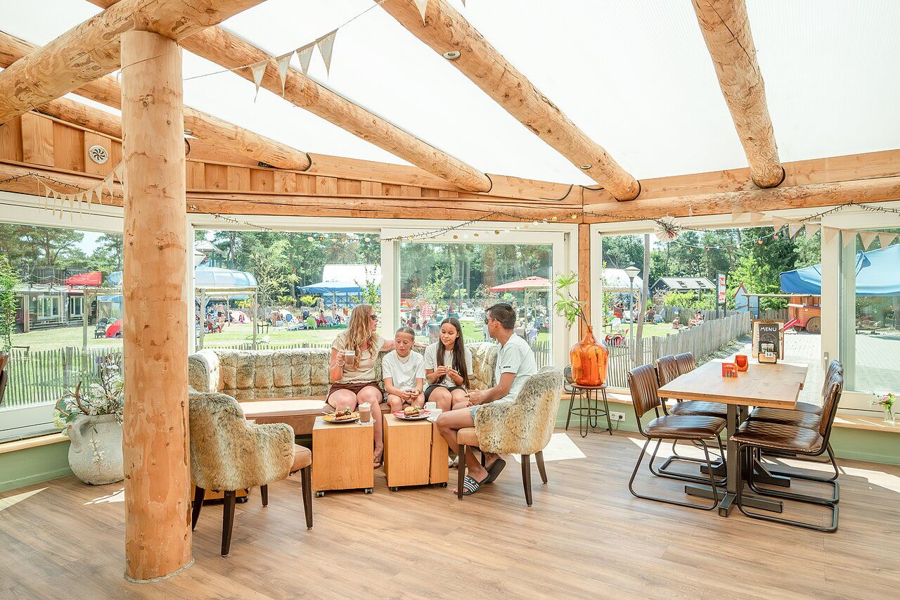 Familie entspannt im Restaurant/Bar des Campingplatzes CAPFUN De Scheepsbel in Doornspijk.