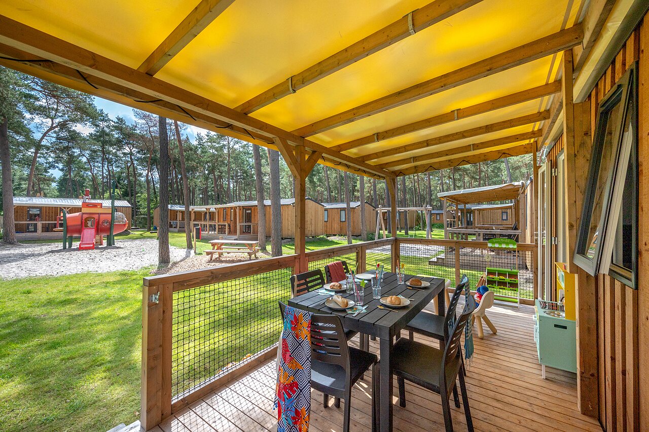 M�blierte Terrasse eines Mobilheims mit Spielplatz auf dem Campingplatz CAPFUN De Scheepsbel in Doornspijk.