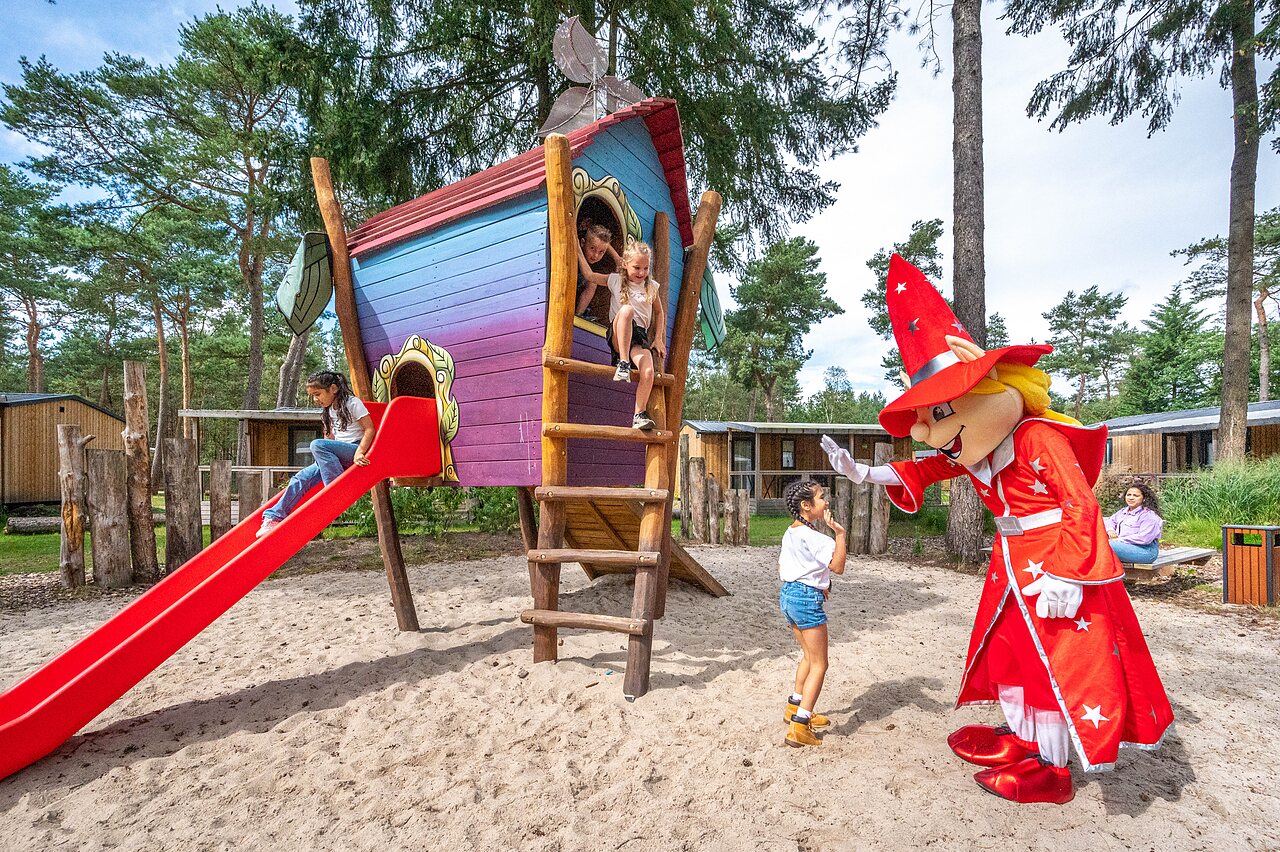 Spielplatz mit Rutsche, Baumhaus und Maskottchen auf dem Campingplatz CAPFUN De Scheepsbel in Doornspijk.
