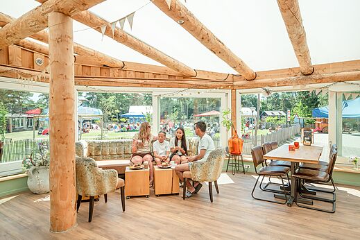 Familie isst im hellen Restaurant des Campingplatzes CAPFUN De Scheepsbel in Doornspijk.