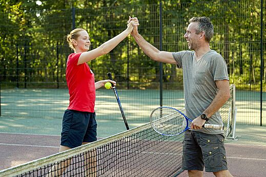 Tennisplatz mit lachenden Spielern auf Camping CAPFUN De Scheepsbel in Doornspijk.