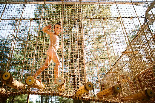 Naturistisch kind speelt op net speeltoestel op camping LIBRANOO Naturiste Belezy.