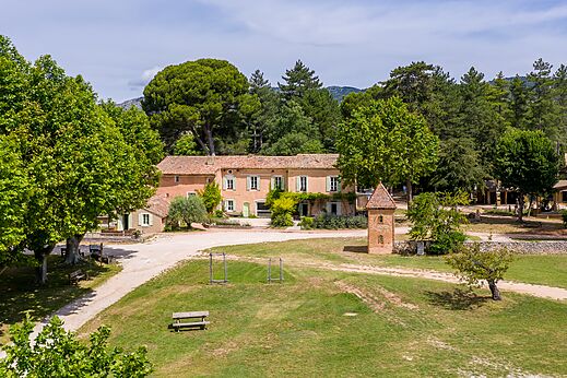 Hauptgebäude und üppiges Grün auf dem Campingplatz LIBRANOO Naturiste Belezy in Bédoin (84).