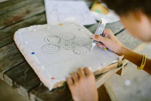 Kind neemt deel aan creatieve schilderworkshop op stof op camping LIBRANOO Naturiste Sabliere in Barjac (30).