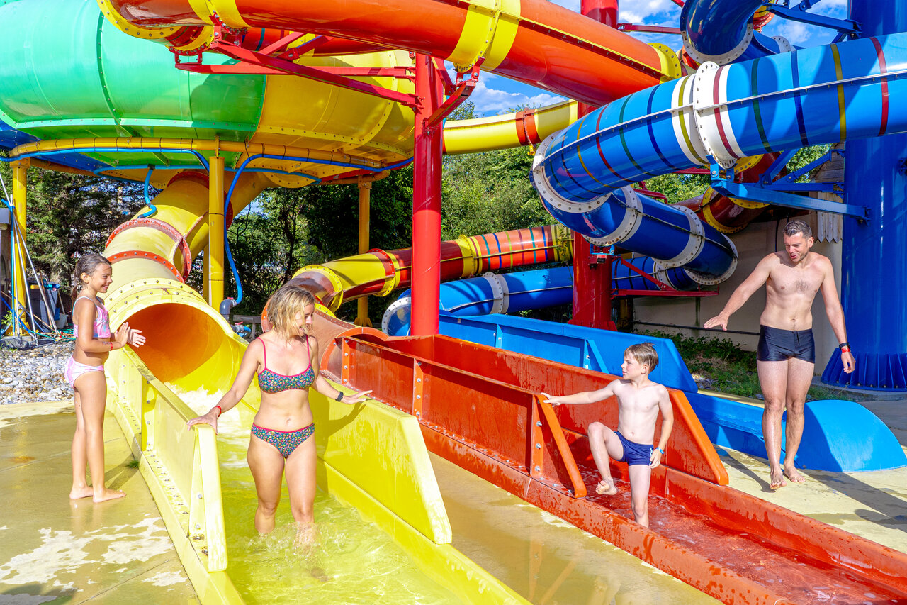 Familie hat Spa� auf bunten Wasserrutschen im Campingplatz CAPFUN Donjon de Lars in Courseulles-sur-Mer.