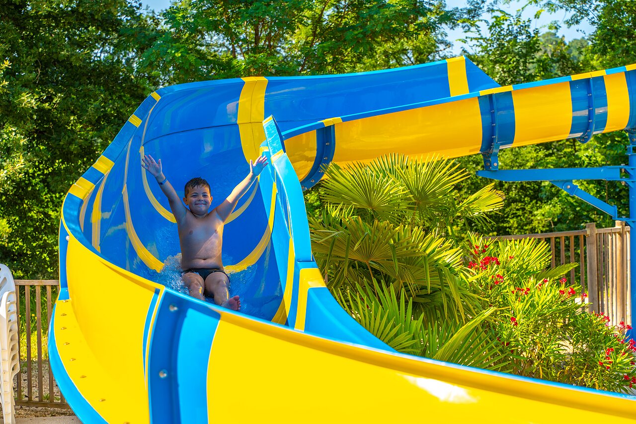 Ni�o feliz en tobog�n acu�tico azul y amarillo en el camping CAPFUN Duravel en Duravel.