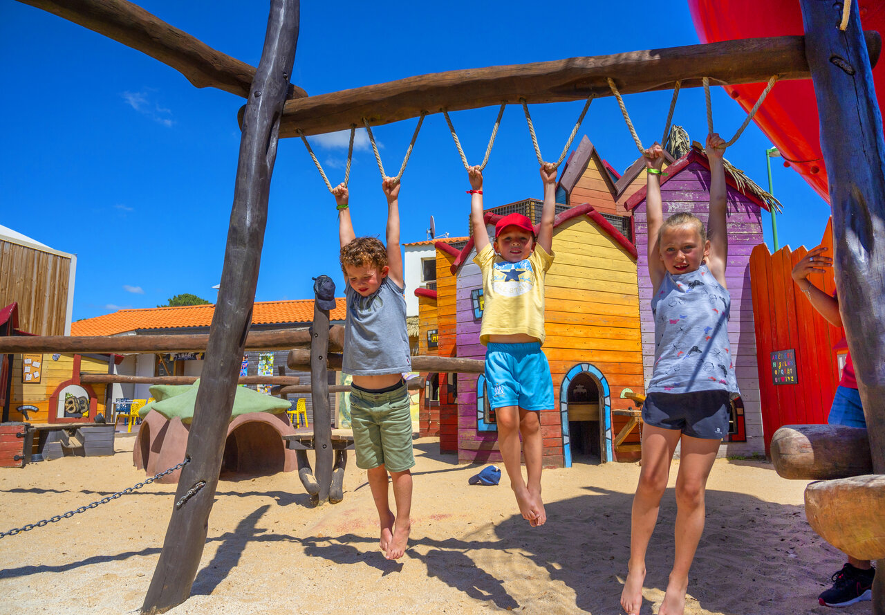 Drei lachende Kinder spielen an Kletterstangen auf dem Campingplatz CAPFUN Ecureuils in JARD SUR MER (85).