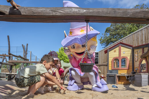 Maskottchen und Kinder spielen auf dem Spielplatz des Campingplatzes CAPFUN Ecureuils in JARD SUR MER.