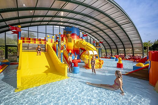 Überdachtes Schwimmbad mit Rutschen und Wasserspielen auf dem Campingplatz CAPFUN Eibernest in Eibergen.