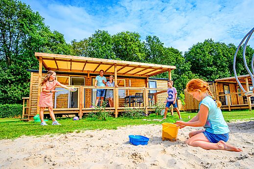 Familie spielt vor einem Holz-Mobilheim auf dem Campingplatz CAPFUN Eibernest in Eibergen.