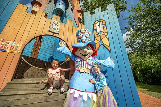 Kinder und Maskottchen vor farbenfrohem Spielplatz auf Camping CAPFUN Eibernest in Eibergen.