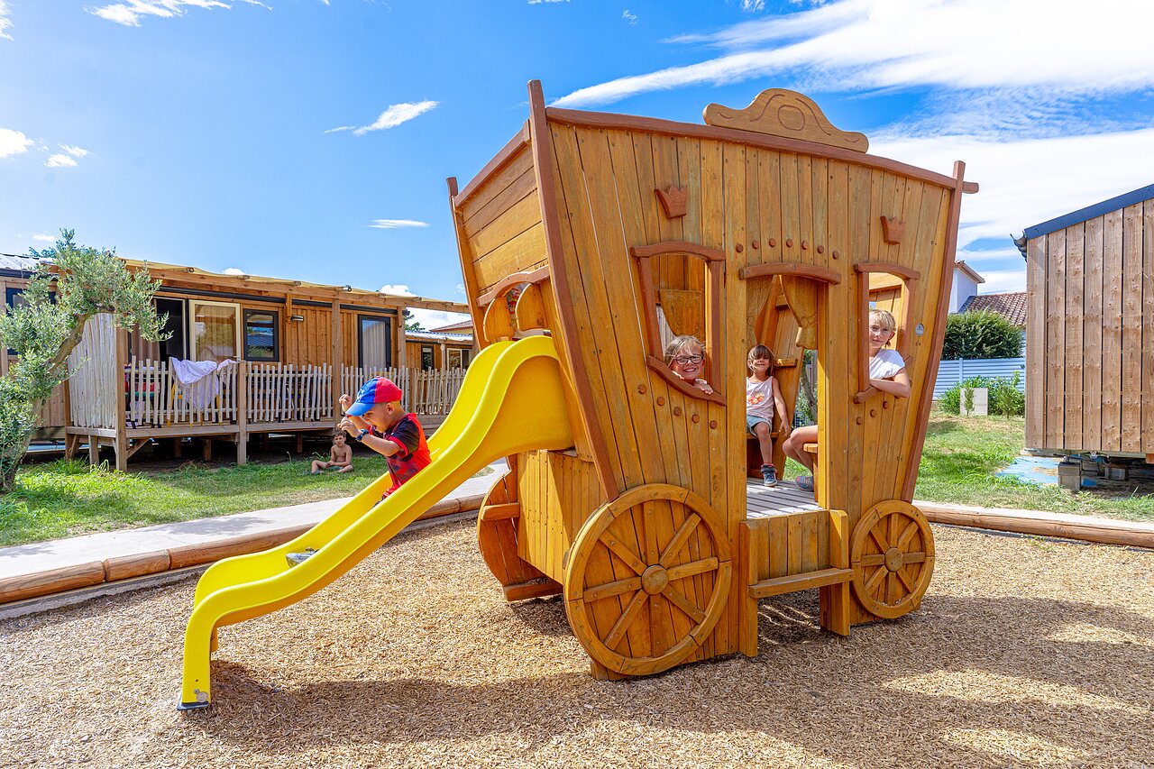 Enfants sur aire de jeux cal�che en bois, toboggan au camping VAGUES OCEANES Elys�e � Le Grau du Roi (30).