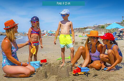 Famille avec enfants jouant sur la plage de sable au camping VAGUES OCEANES Elysée à Le Grau du Roi (30).