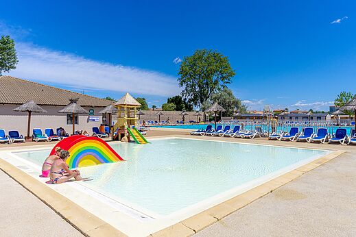 Piscine extérieure, toboggan arc-en-ciel au camping VAGUES OCEANES Elysée à Le Grau du Roi.
