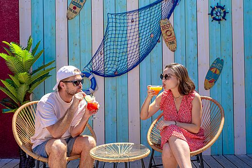Bar ambiance tropicale, couple dégustant des cocktails au camping VAGUES OCEANES Elysée.