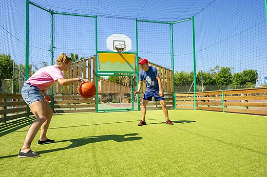 Jeunes jouant au basket sur le terrain multisport au camping CAPFUN El Moli à Elne.