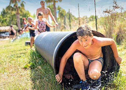 Enfant sortant d'un tunnel aquatique, jeu d'eau au camping CAPFUN El Moli à Elne (66).