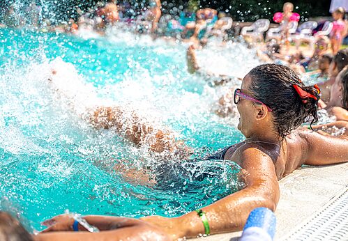 Outdoor swimming pool with bathers and water splashes at CAPFUN Emeraude campsite in Portiragnes (34).