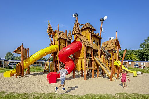 Holzspielplatz mit Rutschen und Kindern auf dem Campingplatz CAPFUN Erkemederstrand in Zeewolde.