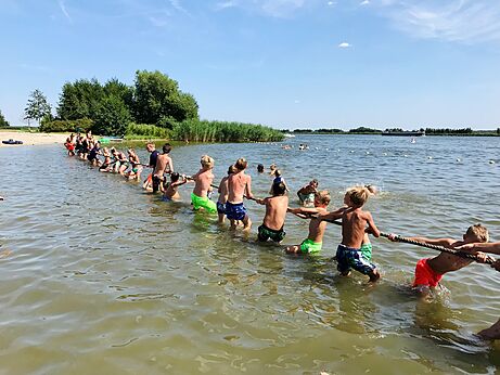 Kinder spielen Tauziehen im Wasser, Campingplatz CAPFUN Erkemederstrand in Zeewolde.