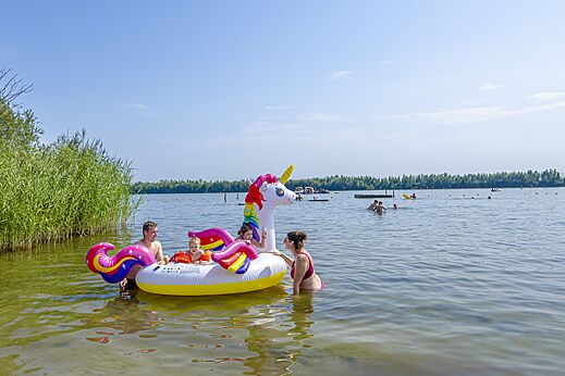 Familie mit aufblasbarem Einhorn im See auf dem Campingplatz CAPFUN Erkemederstrand in Zeewolde.