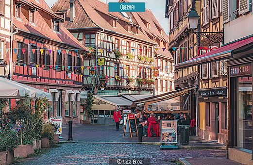 Belebte Kopfsteinpflasterstra�e mit farbenfrohen Fachwerkh�usern in Obernai, Elsass.