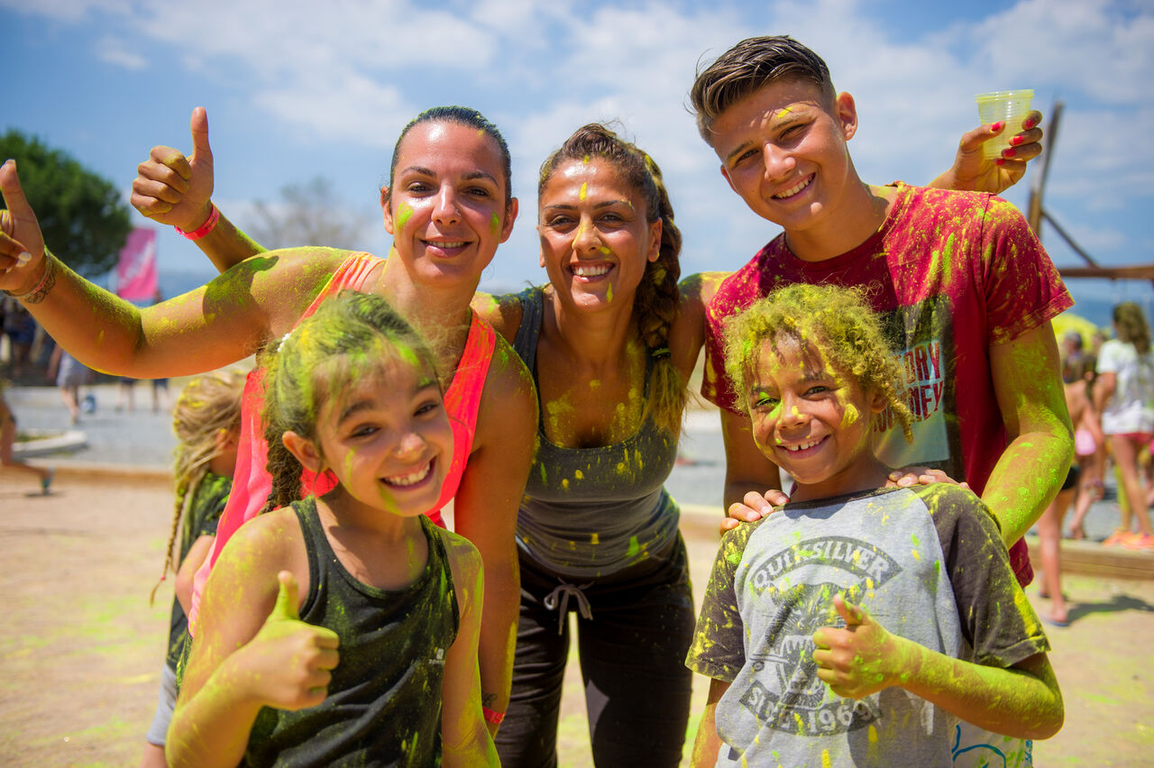 Familia y amigos sonriendo, cubiertos de polvo de colores en una actividad de animaci�n en el camping CAPFUN El Escorial en El Escorial, Madrid.