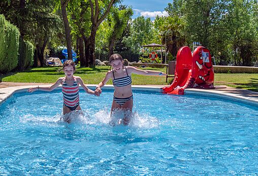 Zwei Kinder spielen im Pool mit Rutsche auf dem Campingplatz CAPFUN El Escorial in El Escorial, Madrid.
