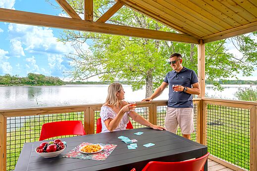 Couple sur terrasse d'hébergement avec vue lac au camping CLICOCHIC Etang de la Mutche à HARPRICH (57).