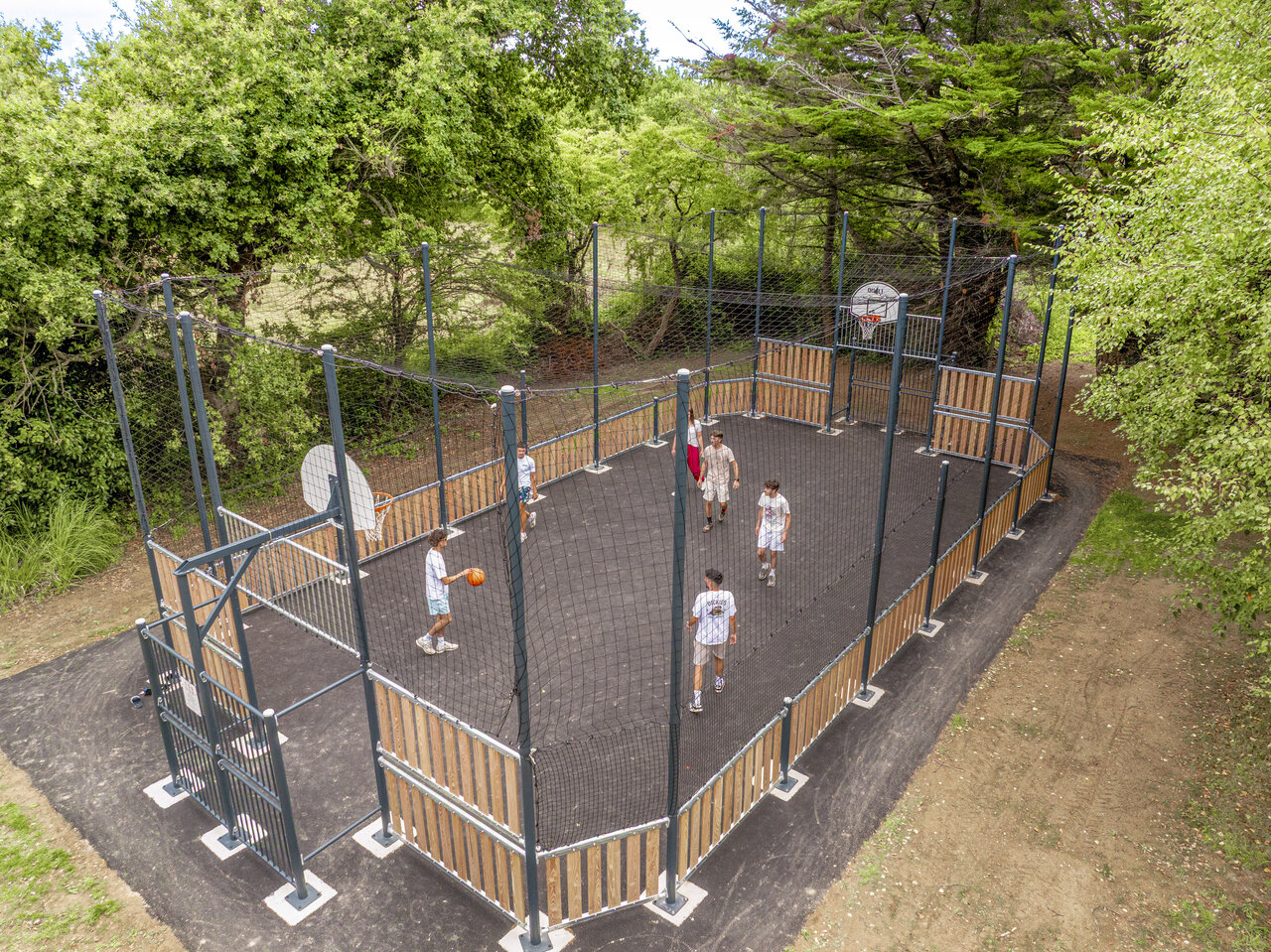 Multisportterrein met jongeren die basketballen op camping CLICOCHIC Etoile de Mer, Asserac (44).