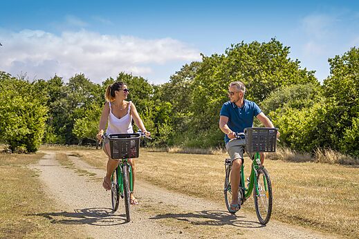 Couple cycling on path at CLICOCHIC Etoile de Mer campsite in Asserac
