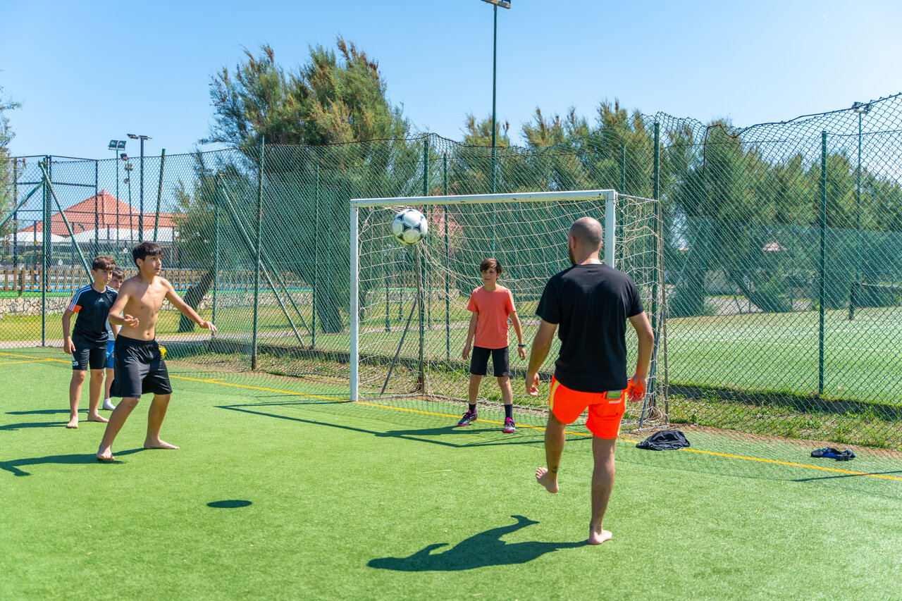 Gasten voetballen op synthetisch sportveld op camping CAPFUN Europing Tarquinia.