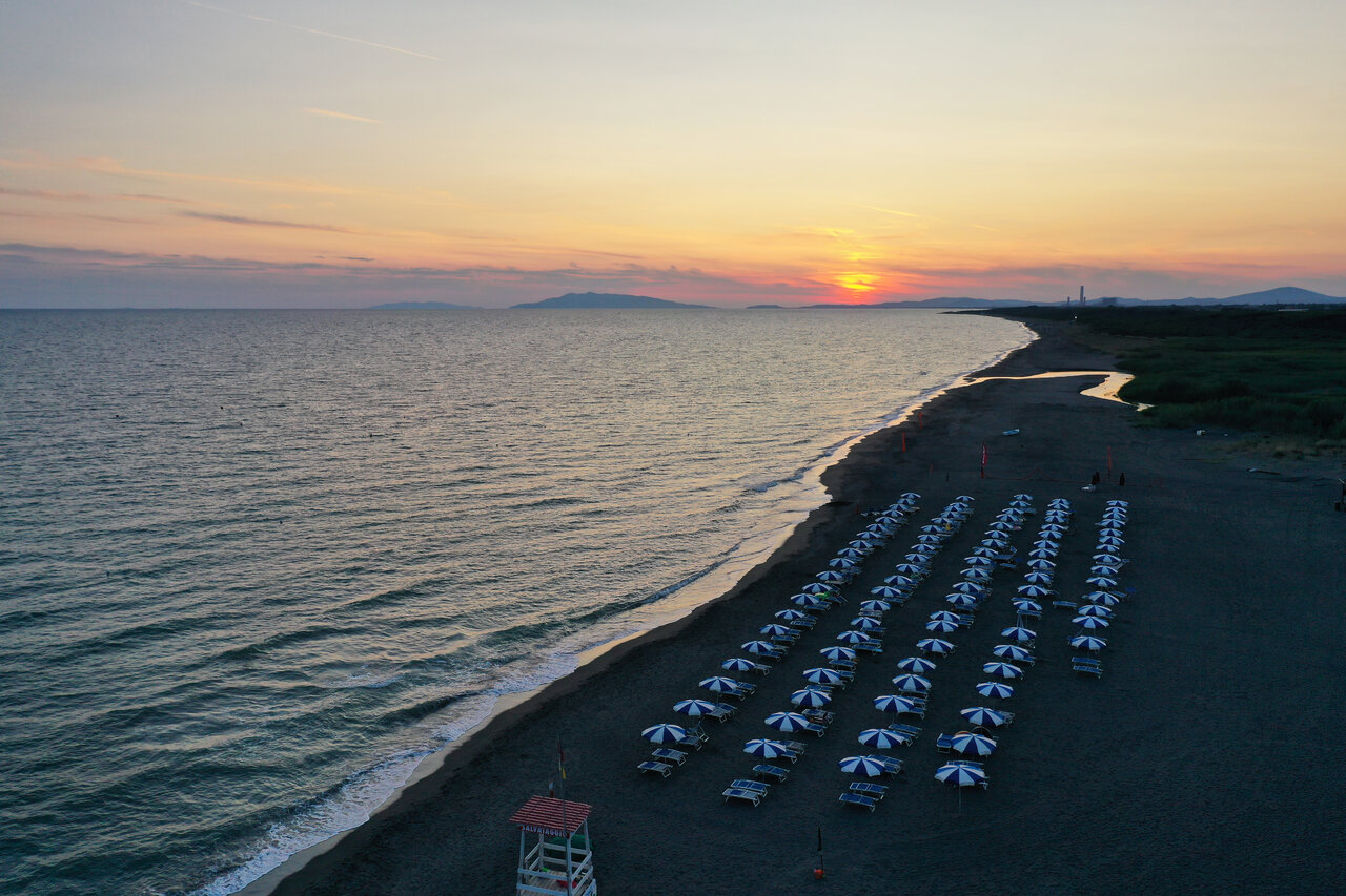 Uitgerust strand met parasols en ligbedden bij zonsondergang, CAPFUN Europing Tarquinia.